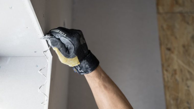 Close-up of a gloved hand applying plaster to a wall indoors in Falun, Sweden.