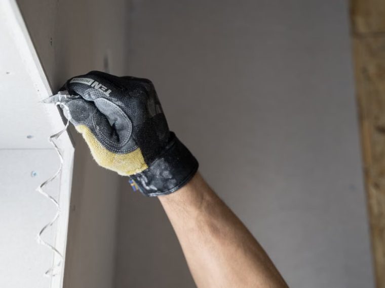 Close-up of a gloved hand applying plaster to a wall indoors in Falun, Sweden.
